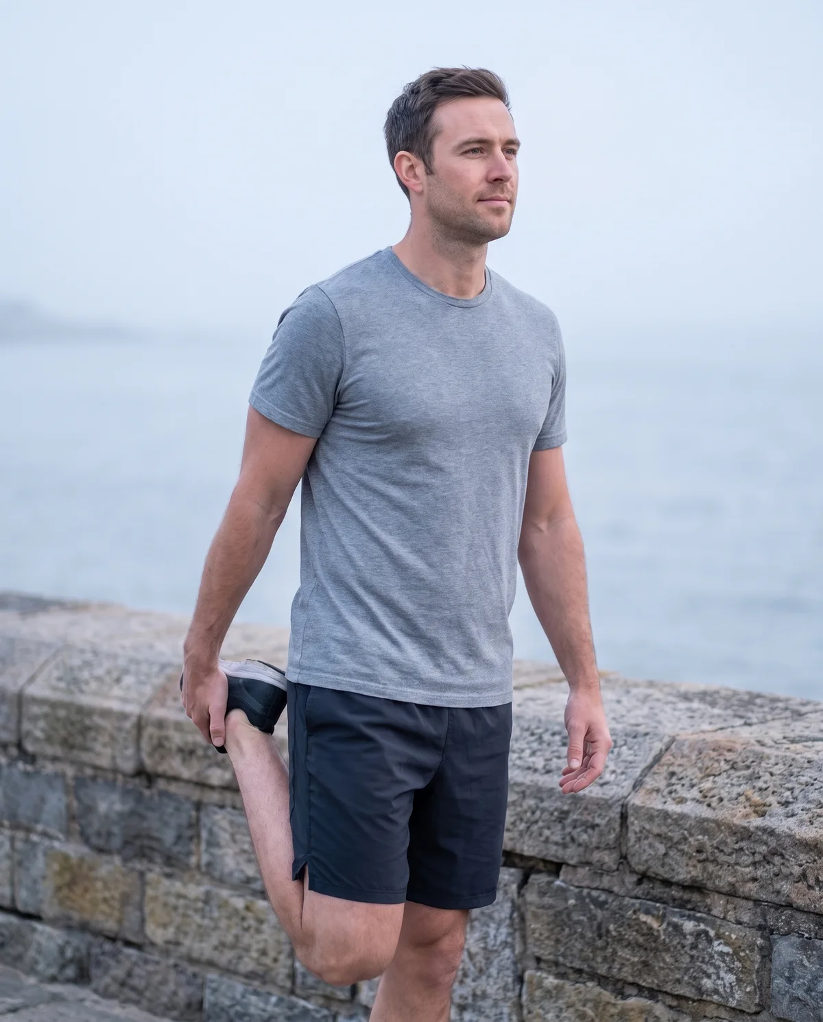 A man stretching on a seaside promenade after a run
